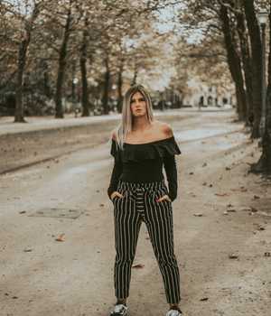 Model in long black trousers with white vertical stripes