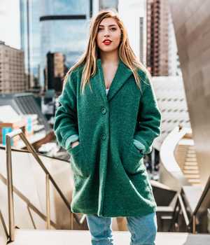 Model in long woolen coat in green, and with 2 buttons and comfortable pockets